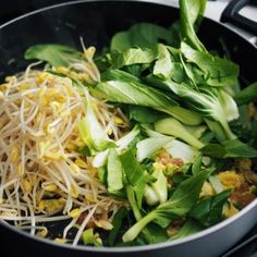 a close up of food in a pan on a stove top with vegetables and noodles