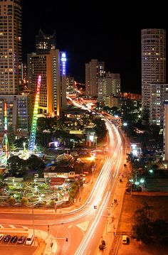 an aerial view of a city at night with traffic and tall buildings in the background