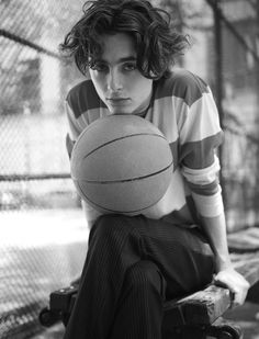 a young man sitting on a bench holding a basketball