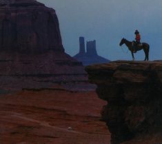 a man riding a horse on top of a cliff