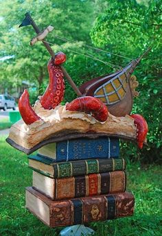 an octopus is sitting on top of some books in the grass with a boat and anchor