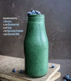 a green smoothie with blueberries in a mason jar on top of two books