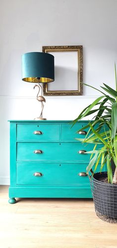 a blue dresser with a potted plant next to it