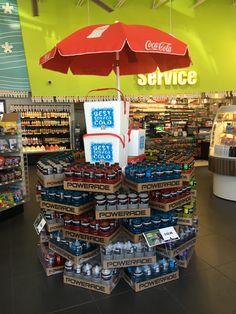 a large display in a grocery store filled with sodas and cans under an umbrella