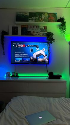 a laptop computer sitting on top of a bed next to a flat screen tv in a room