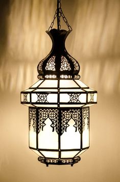 a light fixture hanging from the ceiling in a room with white walls and shadows on it