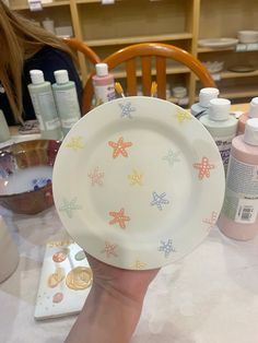 a person holds up a plate with starfish designs on it, while other items sit in the background