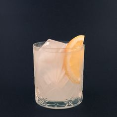 a glass filled with ice and an orange slice sitting on top of it's side