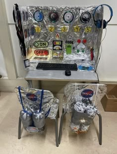 two metal buckets sitting next to each other on top of a computer desk covered in plastic