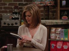 a woman sitting at a table in front of a counter looking at a tablet computer