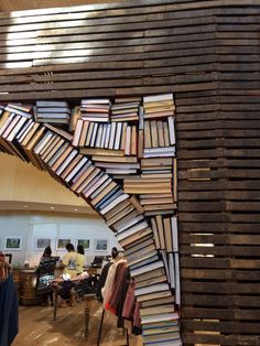 a large stack of books sitting on top of a wooden floor next to a wall