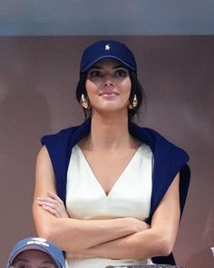 a woman with her arms crossed wearing a blue hat