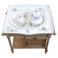 an old wooden table with two dishes on it and a tea pot in the middle