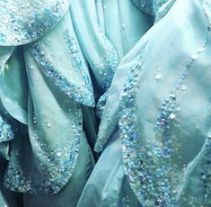 many blue dresses with sequins on them are stacked up in a pile together