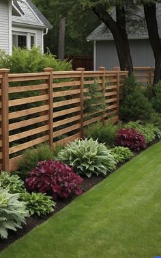 a wooden fence surrounded by plants and flowers