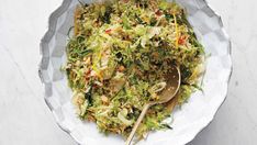 a white bowl filled with salad and a wooden spoon on top of a marble table