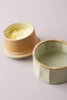 two bowls with food in them sitting on a table next to each other and one is empty