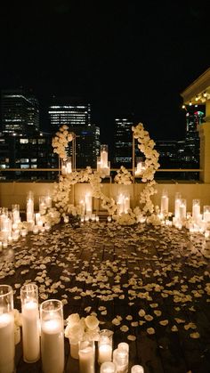 many candles are lit on the ground in front of some buildings and skyscrapers at night