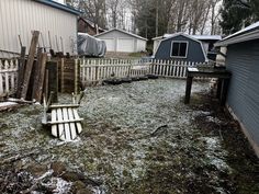 a yard with snow on the ground and wooden slats in front of it, surrounded by houses