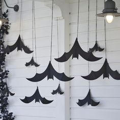 black paper bats hanging from the side of a white building with light bulbs on them