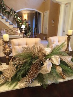 a christmas centerpiece with pine cones, greenery and candles on a dining room table