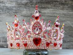 For adults, not suitable for children.  This HUGE crown is too heavy for children.   The crown is adorned with glass rhinestones, crystal beads, and resin hearts on a gold base.  There are loop ends to attach your crown with pins or elastic.   The crown weighs 13.5 ounces (nearly a pound).  The diameter across is 6.5 inches.  It is 5 inches tall at its highest point.   Ships in a box for safe travels! Shipping Details: All items will be shipped First Class by the United States Postal Service. An Bridget Cosplay, Queen Of Hearts Crown, Disney Princess Gowns, Resin Hearts, Crown Pink, Heart Crown, Pink Crown, Egyptian Style, Safe Travels