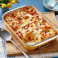 a casserole dish with meat and vegetables in it on a cutting board next to flowers