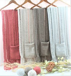 crocheted blankets and balls of yarn hanging on a clothes rack with flowers in the foreground