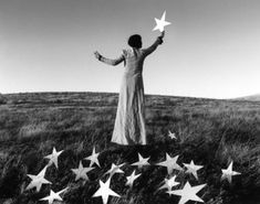 a woman standing on top of a grass covered field holding a star in the air