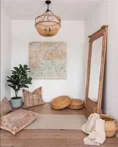 a room with a mirror, pillows and a potted plant on the floor in front of it