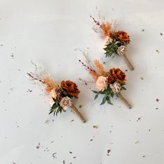 three boutions with dried flowers and leaves on a white surface