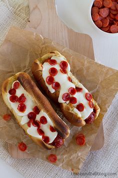 two hot dogs covered in toppings sitting on top of wax paper next to each other