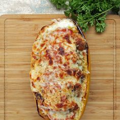 a cheesy dish on a cutting board with parsley