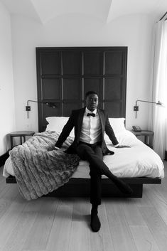 a man in a tuxedo sitting on a bed