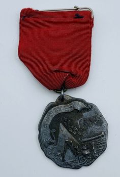 a medal with a red ribbon around it and an elephant on the front, sitting on a white surface