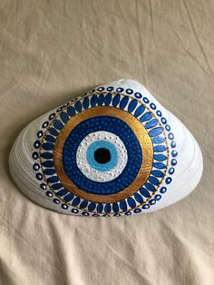 an eyeball painted on top of a white shoe with blue and gold accents is shown