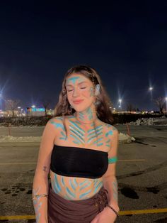 a woman with painted body art standing in a parking lot