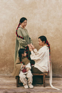 two women and a child sitting on a chair with one holding the other's hand