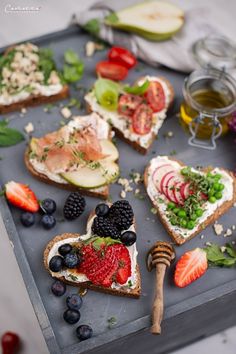 an assortment of fruits and sandwiches on a tray