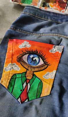 an eye patch on the back of someone's jean pants, which has been painted with acrylic paint