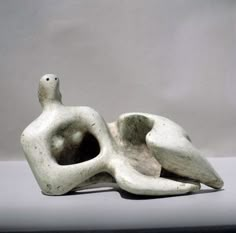 a white sculpture with a bird on it's back sitting in front of a gray background