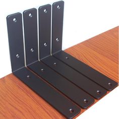 three black metal brackets on a wooden table