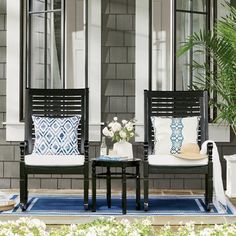 two chairs sitting on top of a blue rug in front of a window next to a potted plant