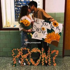 a man and woman standing next to each other in front of a sign with flowers on it