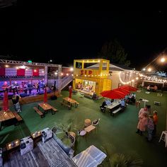 a group of people standing around tables with umbrellas on top of them at night