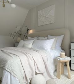 a bed with white linens and pillows in a small room next to a dresser