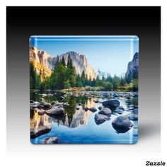 a glass plate with rocks and trees in the water near some mountain peaks, on a black background