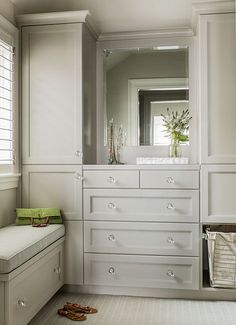 a bathroom with white cabinets and drawers