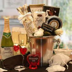 a gift basket with champagne, chocolates, and other items on a table in front of a window