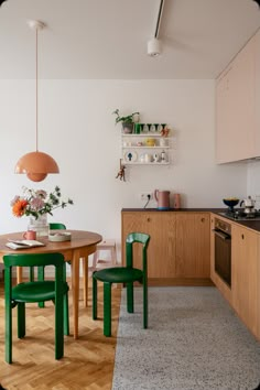 a kitchen with wooden floors and green chairs